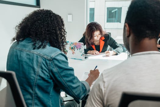 A diverse group of people discussing and filling out documents in a modern office setting.