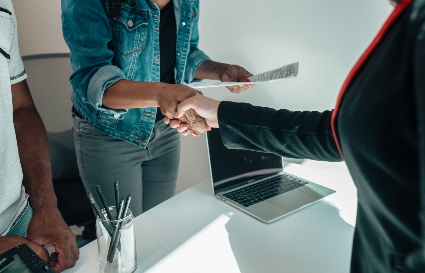 Two people shaking hands over a desk signifies a business agreement or partnership.