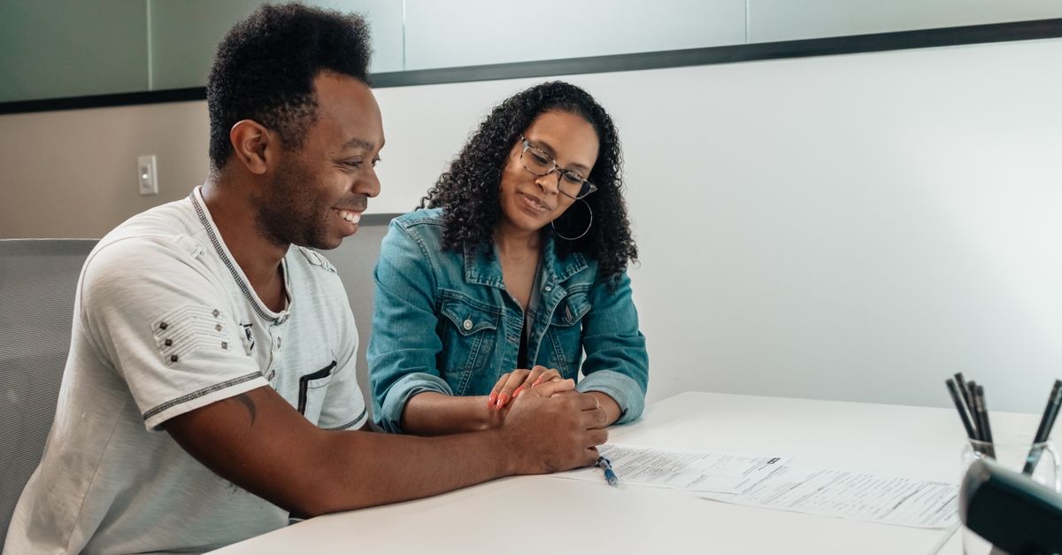 Hispanic woman smiling while reviewing financial documents at a credit union office
