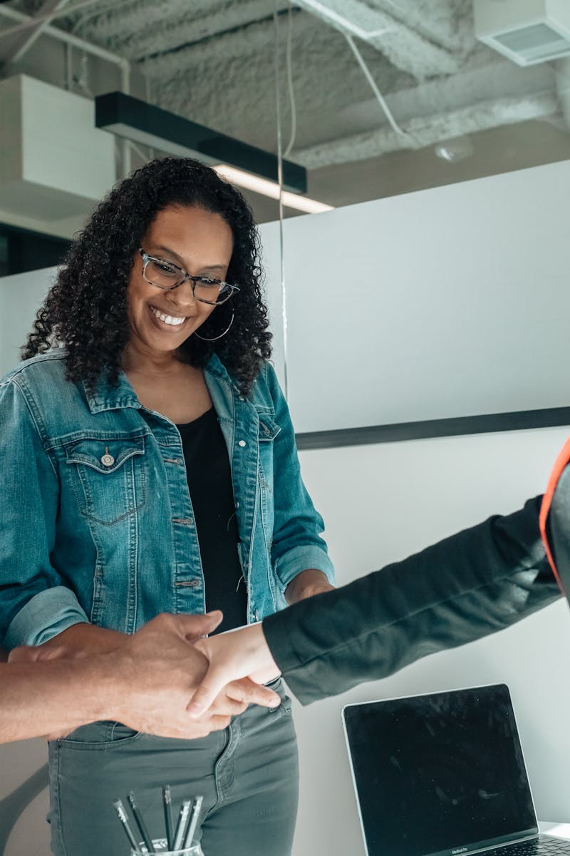Smiling couple shaking hands with advisor in modern office.