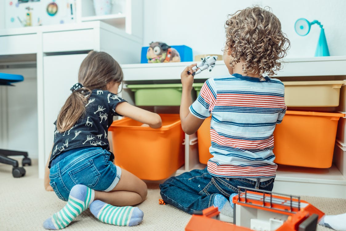 Free Two kids playing with toys and colorful bins in a playful indoor setting. Stock Photo