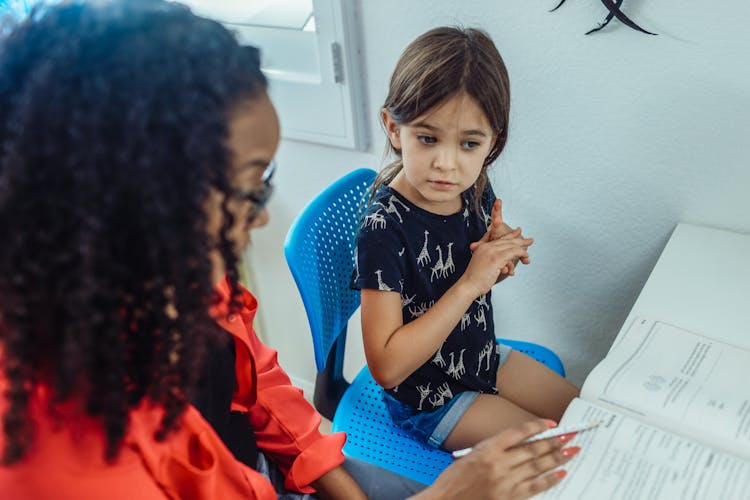 Black Tutor With Workbook Talking To Schoolgirl In House