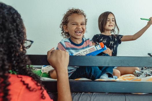 Happy kids playing indoors with toy guns, enjoying their time together.