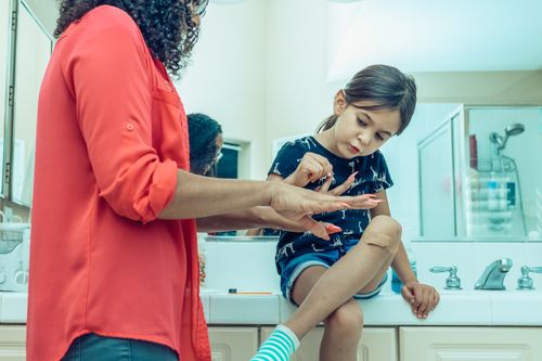 Free A mother applying nail polish to her child's fingernails in a bathroom setting. Stock Photo