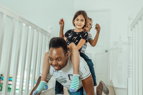 A Boy and a Girl Piggyback Riding a Man