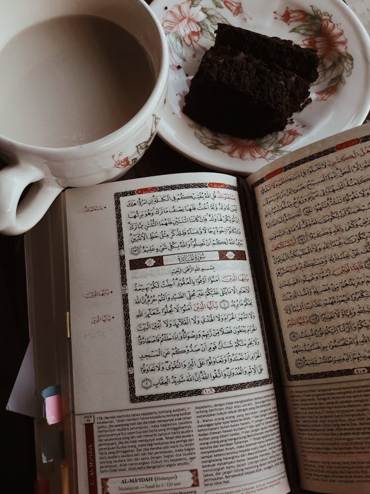 An Open Book Beside A Cup Of Coffee And A Piece Of Cake