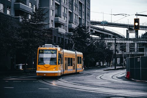 Modern yellow tramway driving on rails on asphalt roadway in residential district of city