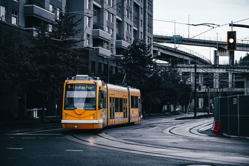 Free Modern yellow tramway driving on rails on asphalt roadway in residential district of city Stock Photo