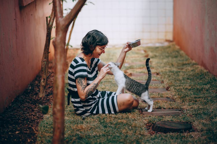 A Cat Licking A Woman's Finger