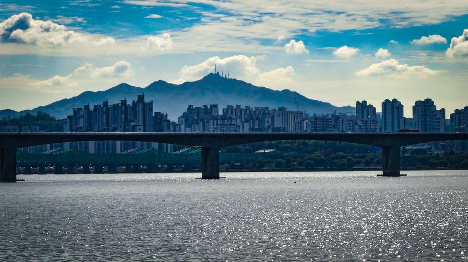 Stunning urban skyline with bridge over water and mountains in the background.