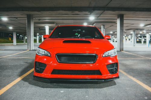 Free Front view of a red car parked in an underground parking garage at night. Stock Photo