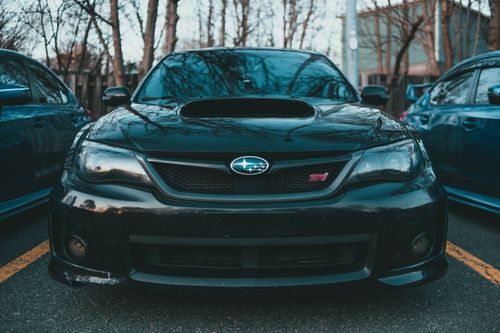 Free Front view of a black Subaru STI parked outdoors with a sporty appearance. Stock Photo