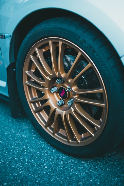 Free Detailed shot of a gold alloy wheel from a sports car on road. Stock Photo