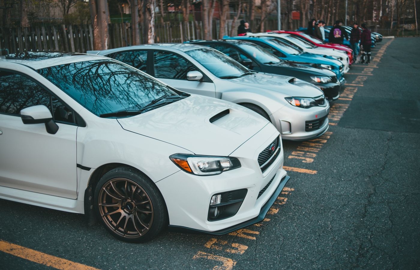 Vibrant lineup of parked cars in an outdoor lot, showcasing various models and colors.
