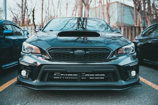 A sleek black Subaru Impreza with a prominent hood scoop, captured in an outdoor setting.