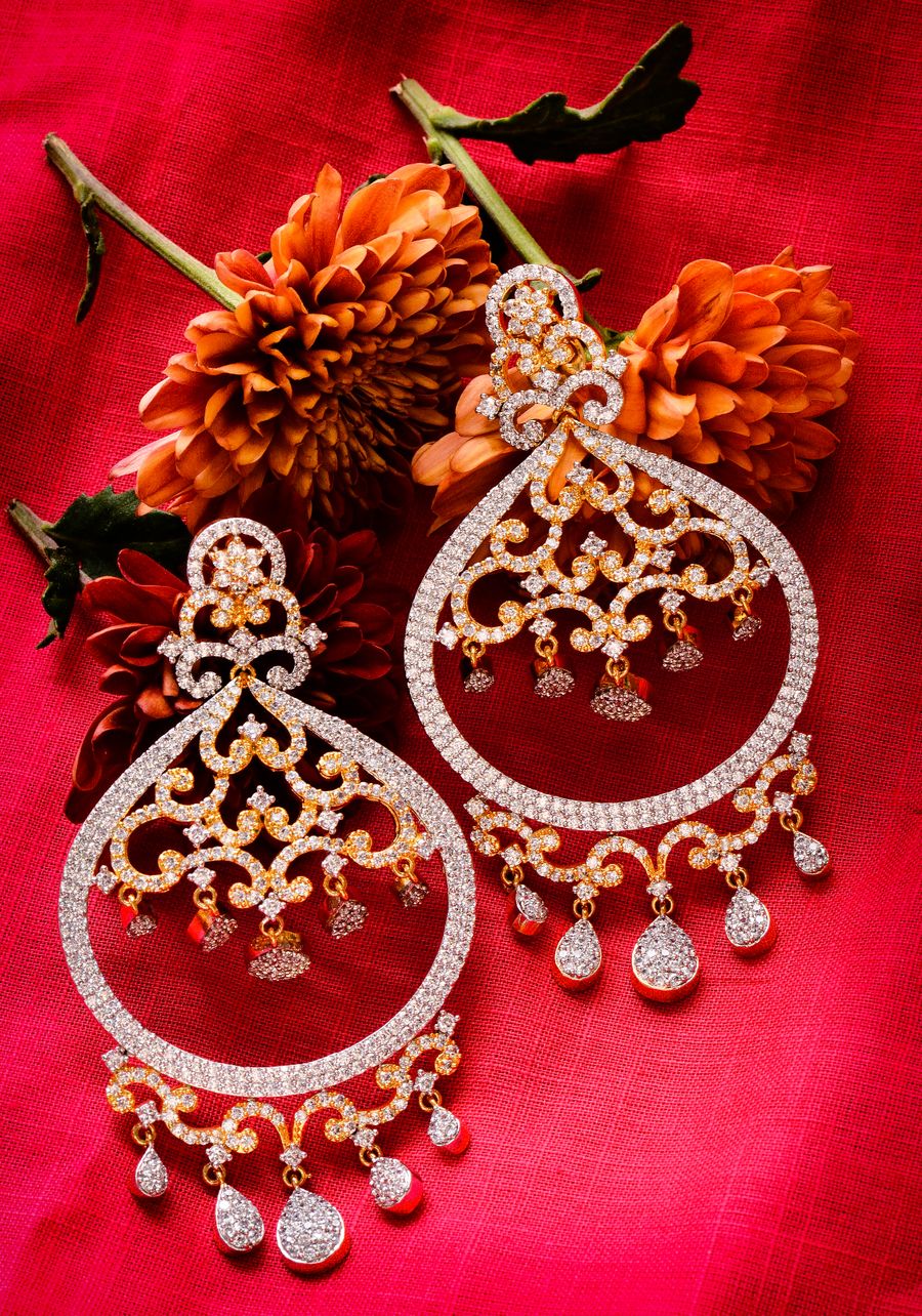 Diamond earrings against a red background with dahlias