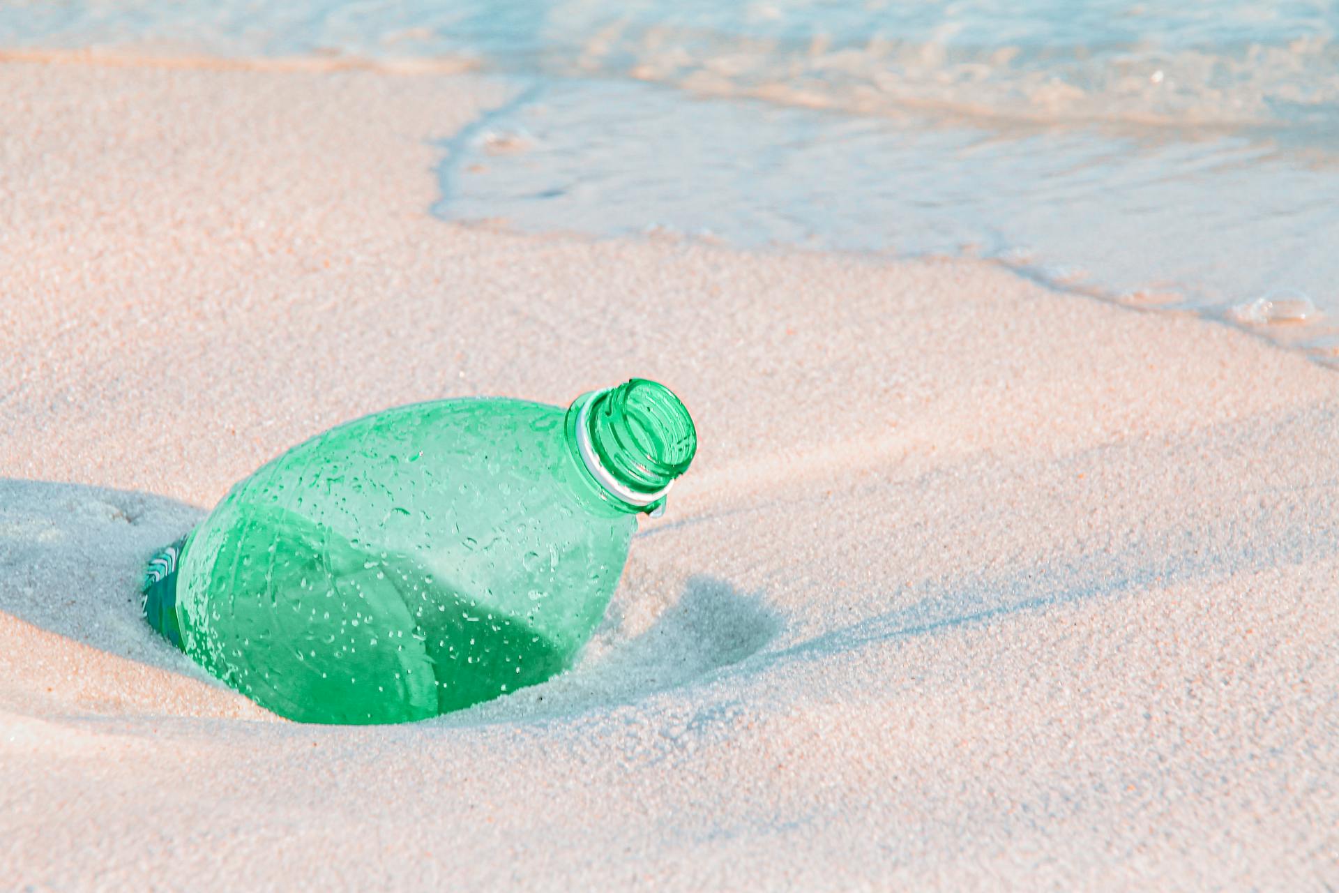 Discarded plastic bottle on the sandy beach illustrating environmental pollution.