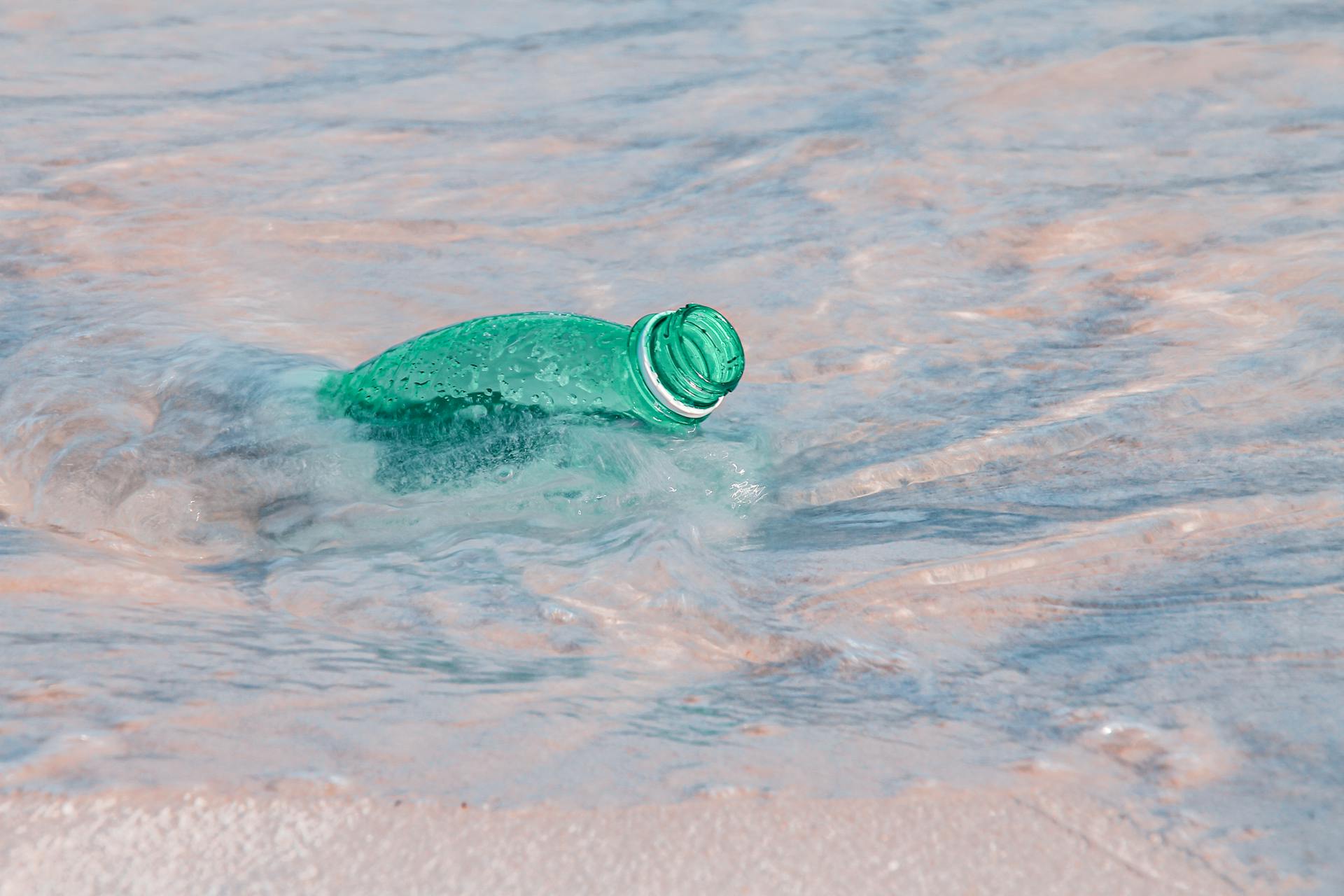 Close-up of a plastic bottle polluting the ocean shore, highlighting environmental issues.