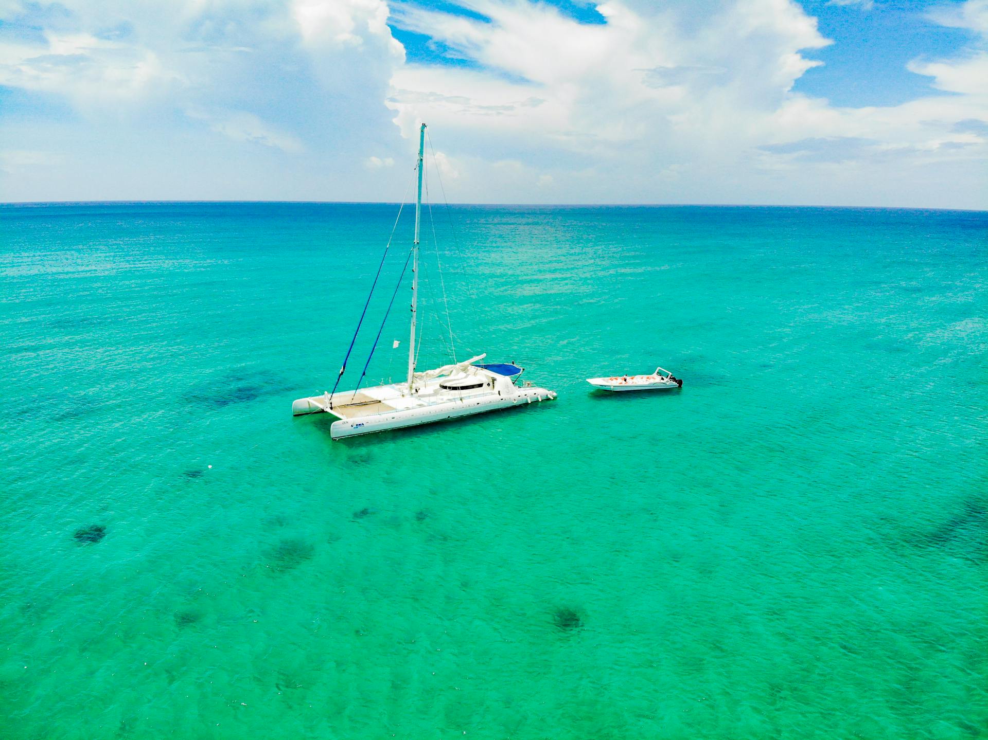 Idyllic view of a catamaran sailing in turquoise tropical waters under a blue sky.