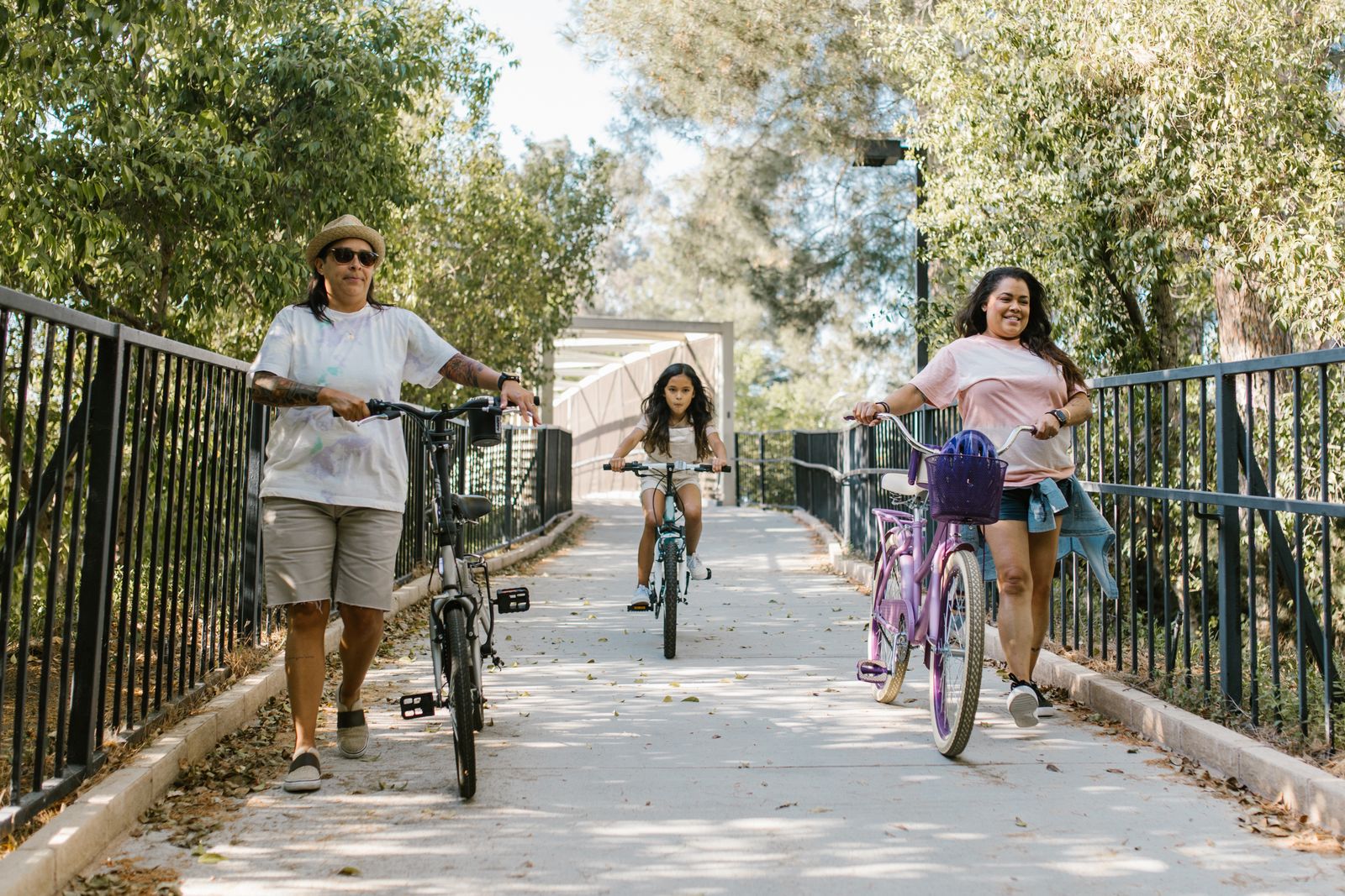 A family cycling together along a leafy park path