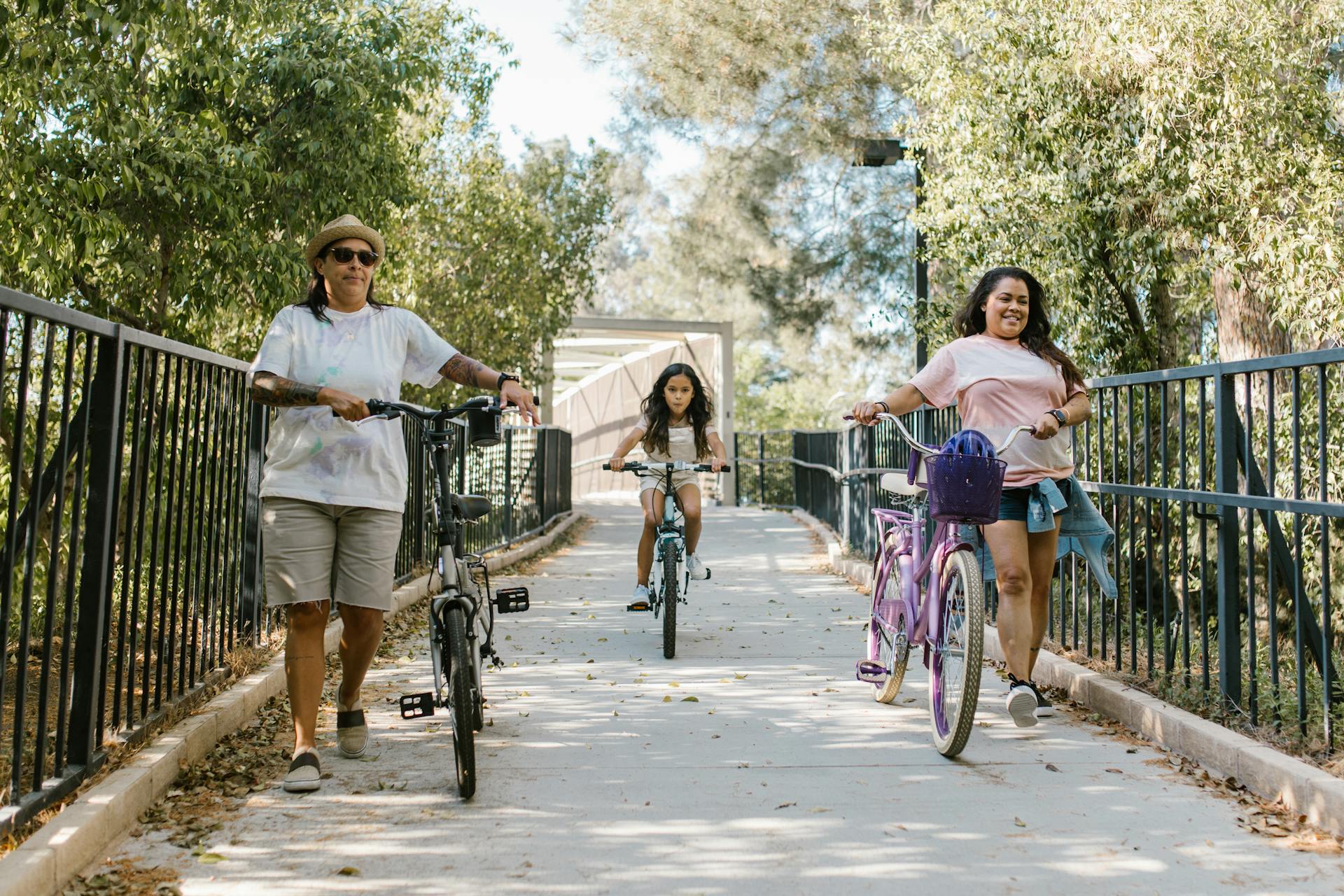 A family of three enjoys a relaxing summer bike ride in a lush, green park setting.