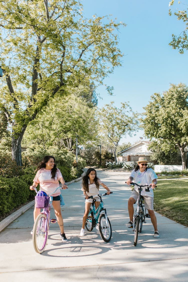 Happy Family Riding Bikes In Alley On Sunny Day