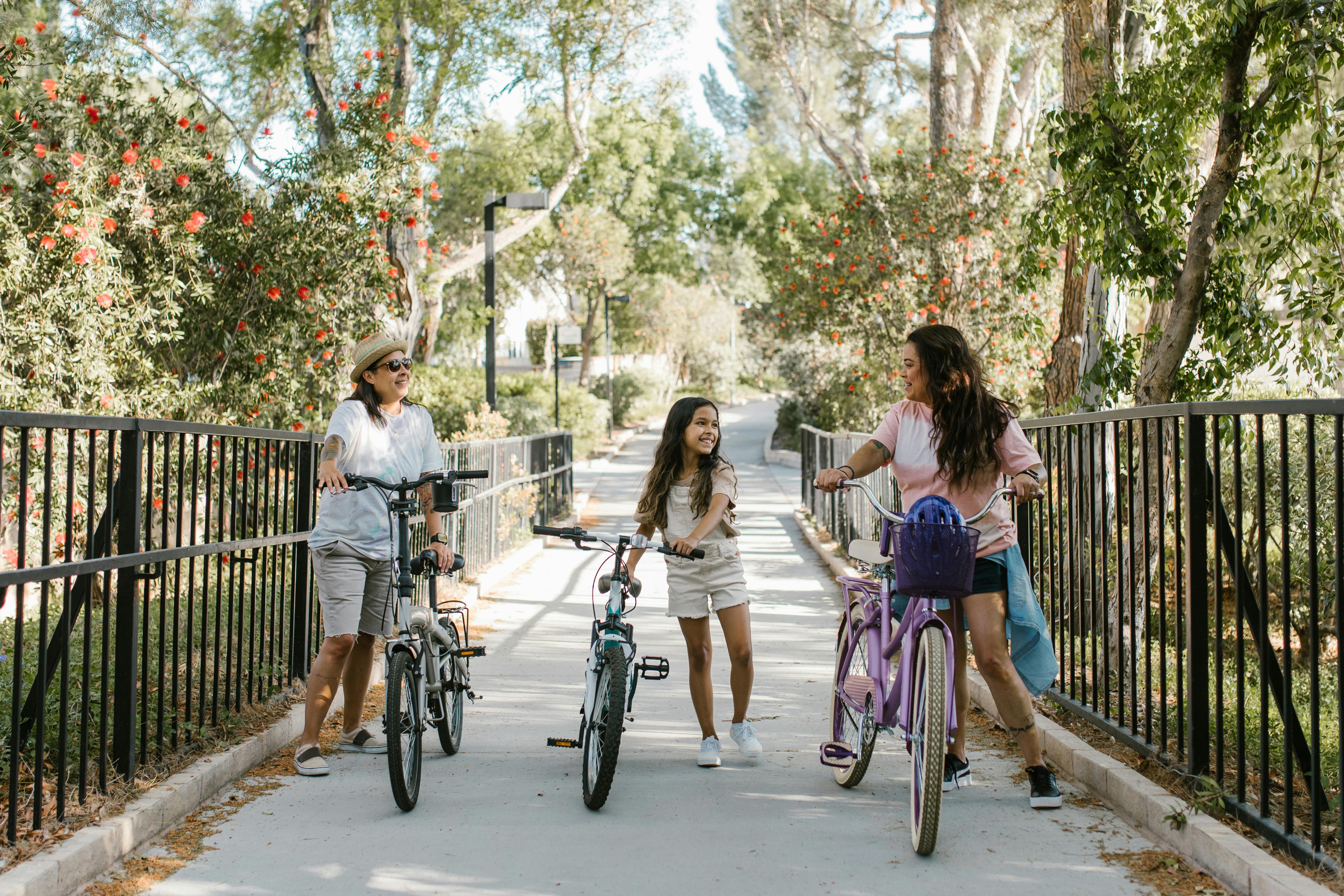 a two women and young girl pushing bicycle