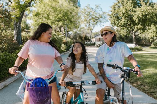 Free Family enjoys a sunny day riding bicycles in a park, fostering happiness and togetherness. Stock Photo