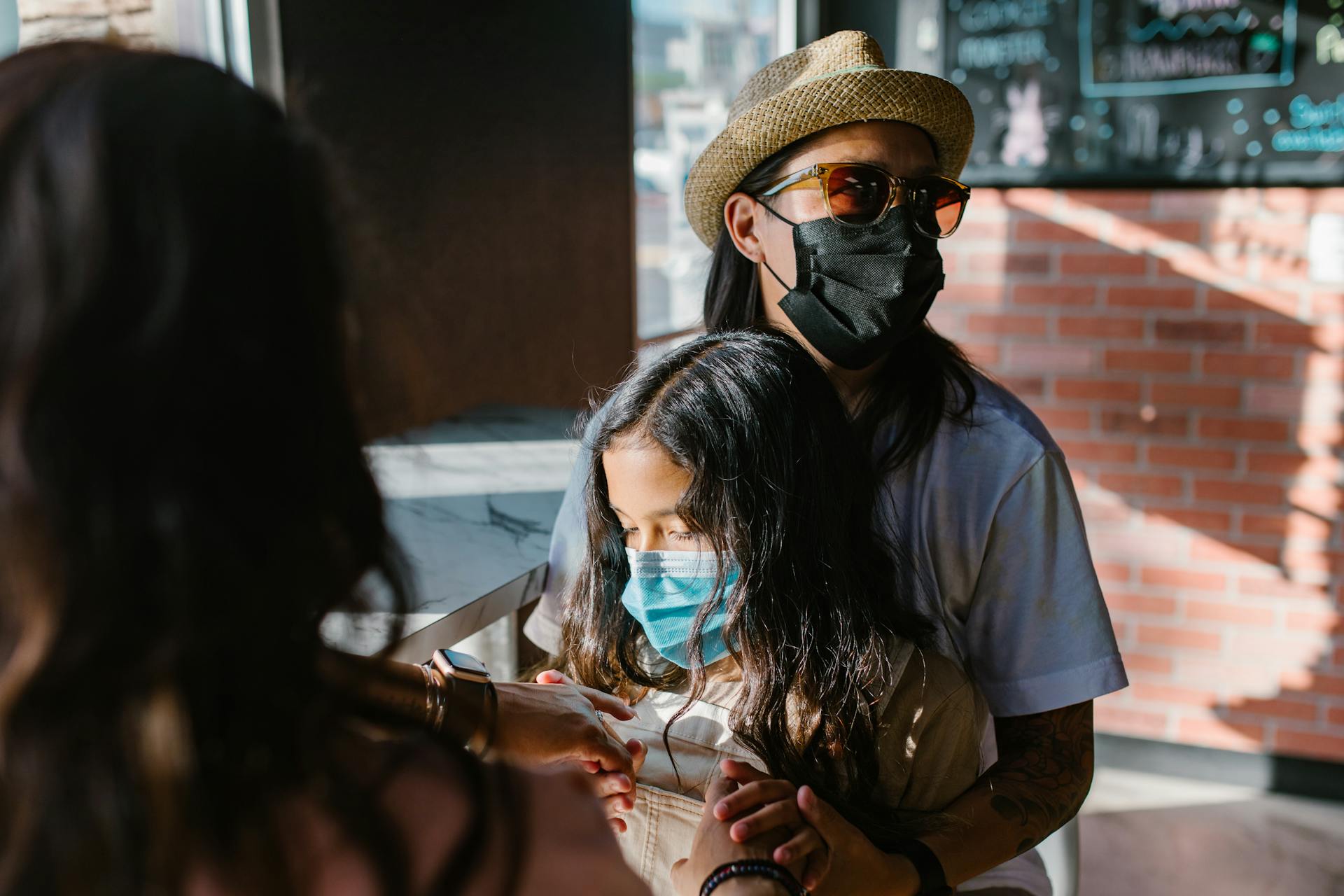 A modern family shares a moment indoors, bonding together while wearing face masks.