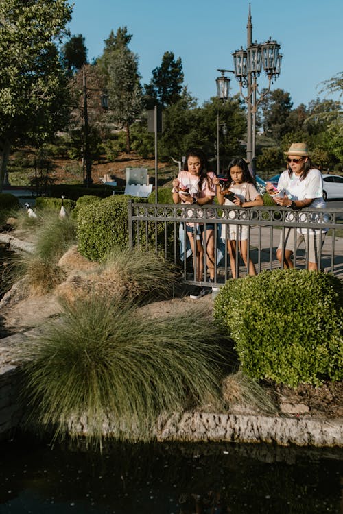 A Family Eating Snacks while Leaning on a Fence