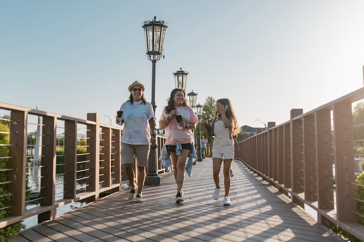 Happy Family Walking On Footbridge In Park