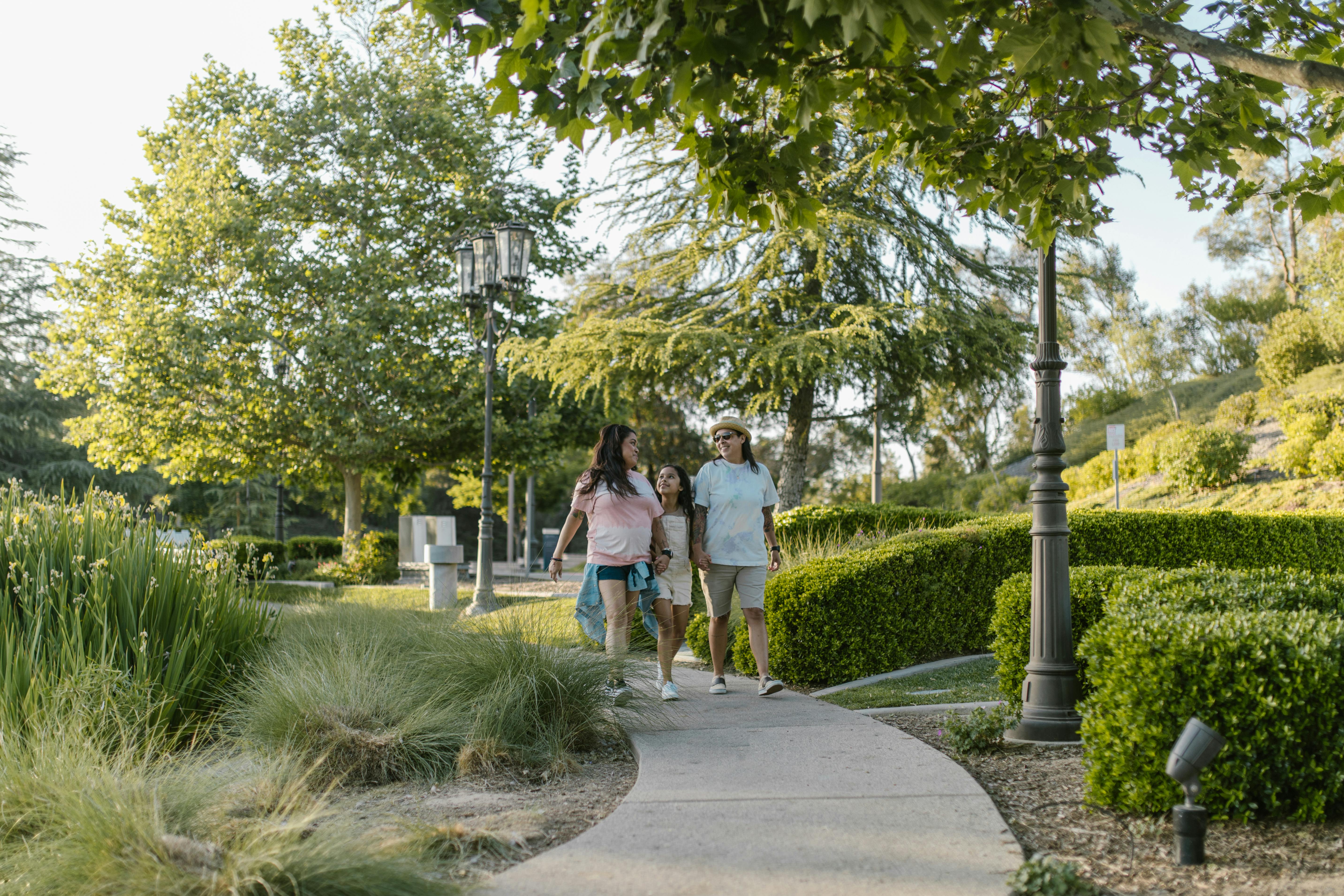 a same sex couple walking with their daughter at the park