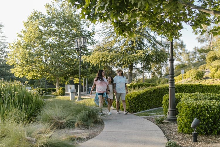 A Same Sex Couple Walking With Their Daughter At The Park