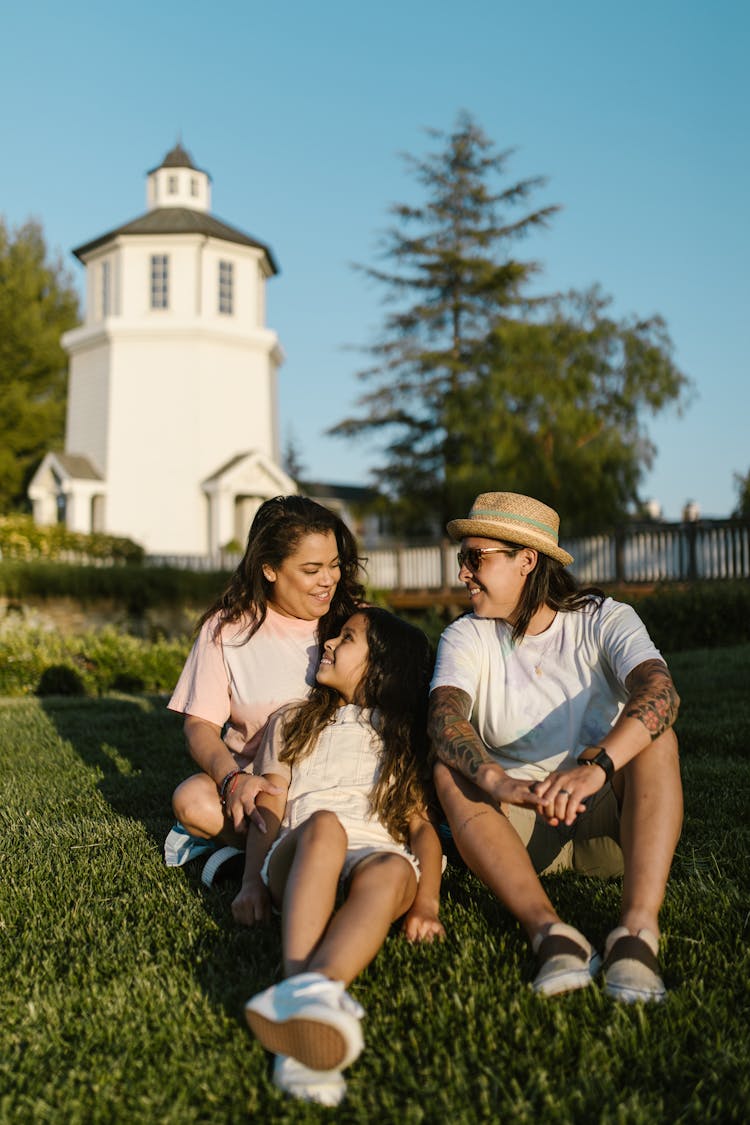 Happy Family Sitting On Grass