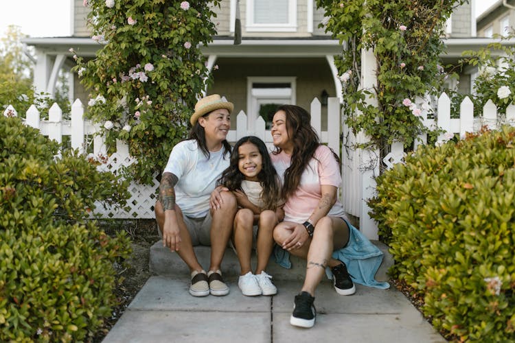 Happy Family Sitting Together In Front Of House