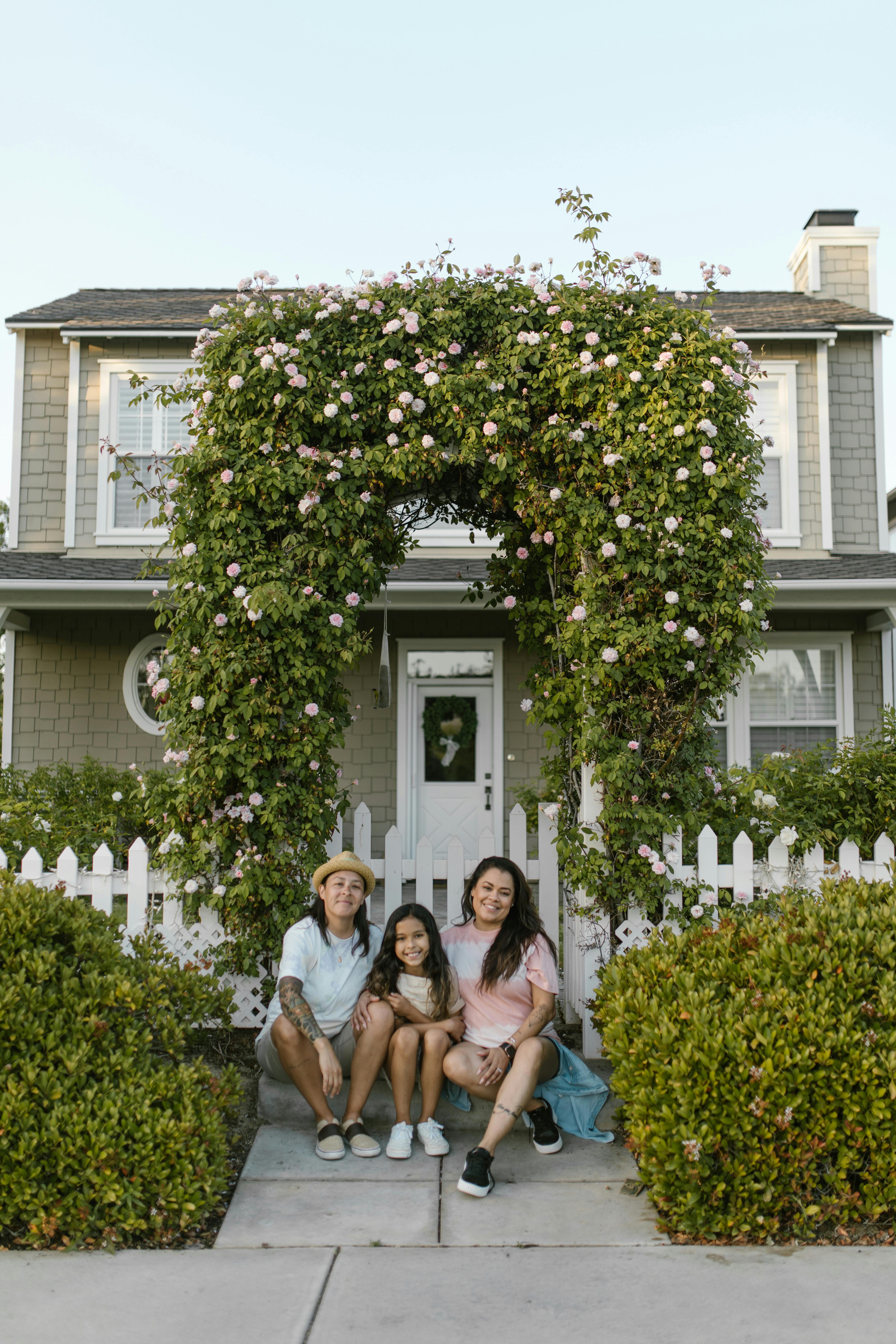 smiling women with girl sitting together in front of a house