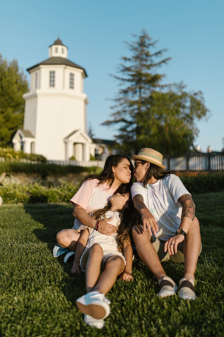 Happy Family Sitting On Green Grass