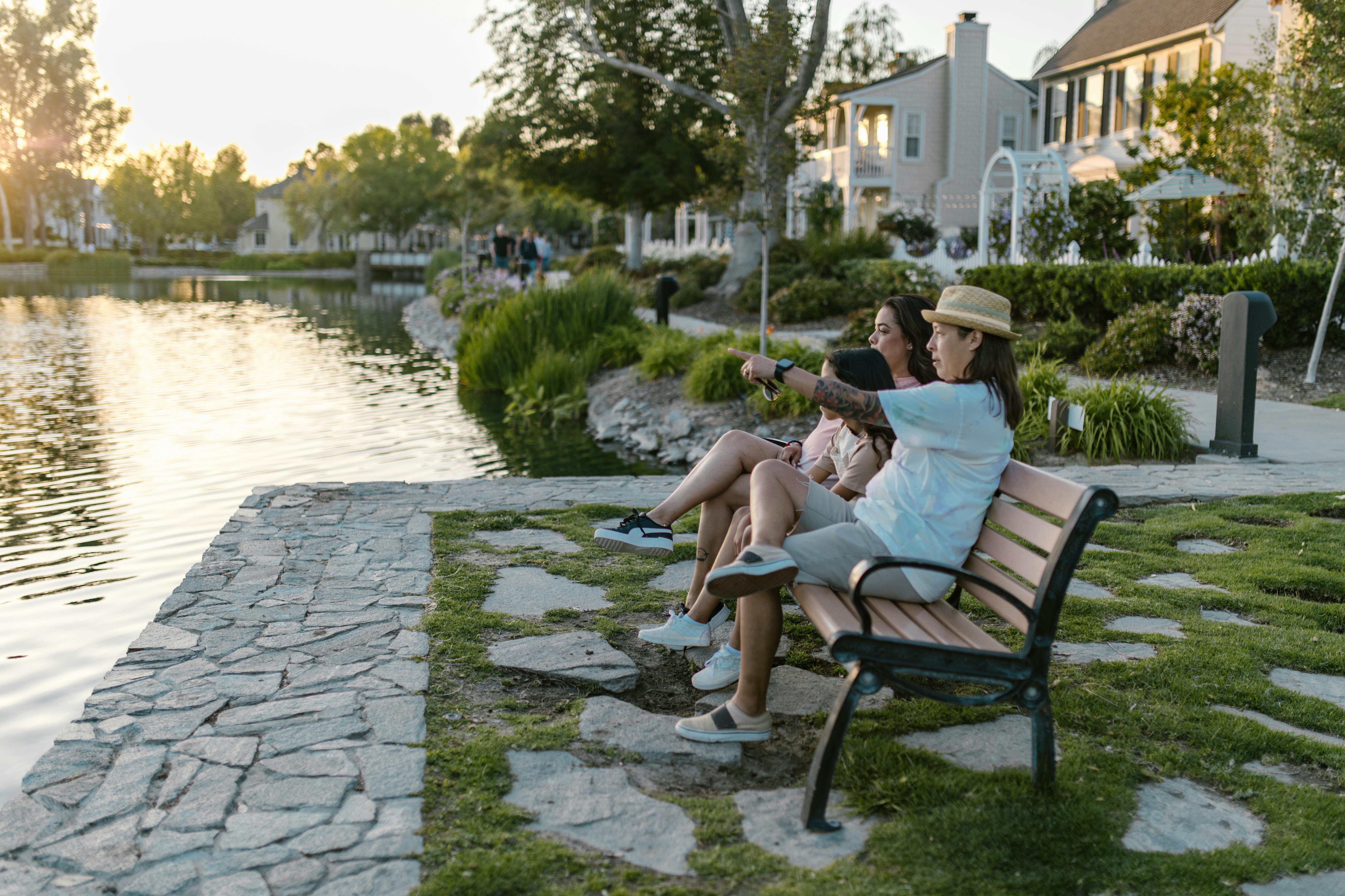 mothers and daughter sitting on a bench by the water