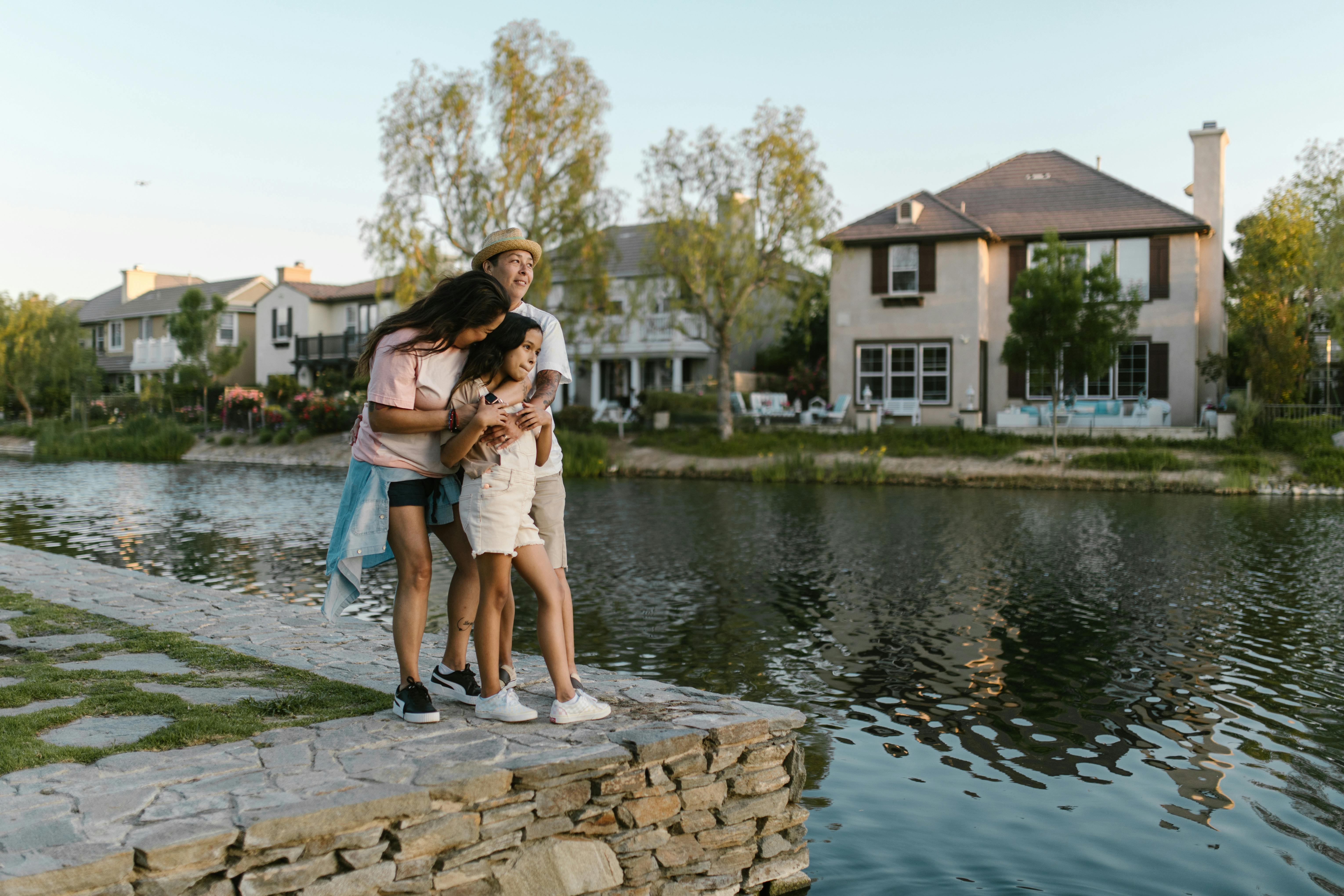 a happy family standing on the lakeside while hugging each other