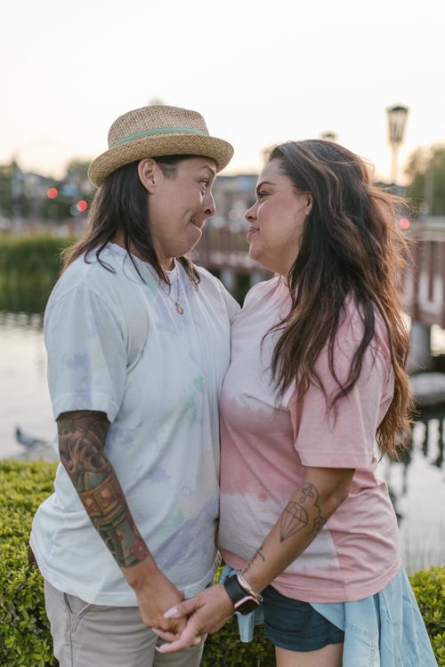 Free Happy LGBTQ+ couple holding hands and smiling in a city park. Stock Photo