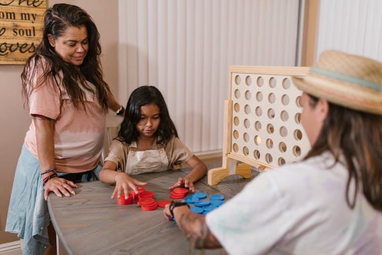 A Family Playing With Chips Of A Connect Game