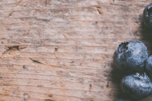 Fresh blueberries on a textured wooden surface, perfect for food photography.