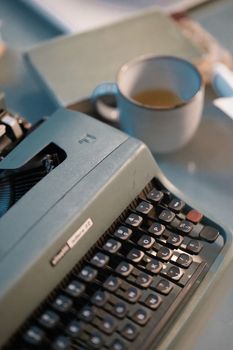 A close-up view of a vintage typewriter next to a coffee mug, illustrating a retro work setup.