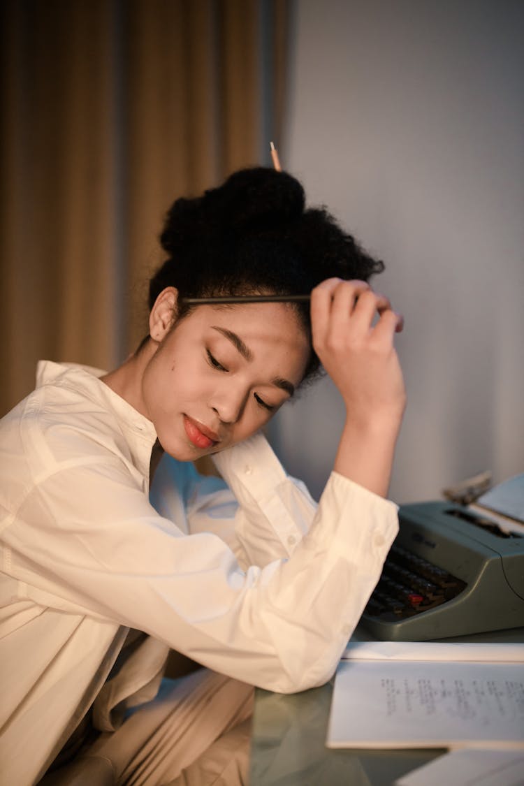 A Woman In White Long Sleeves Thinking While Sitting Near The Table