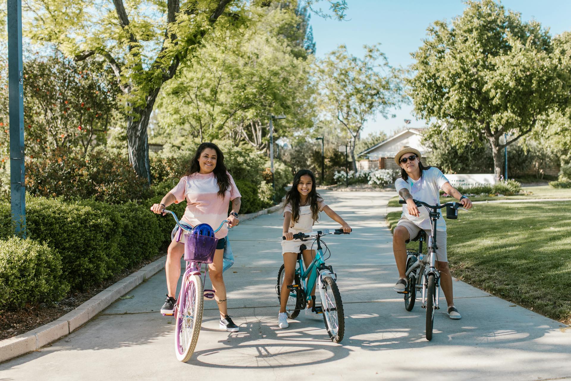 A happy family enjoying a sunny day bike ride in a green park setting, promoting health and togetherness.