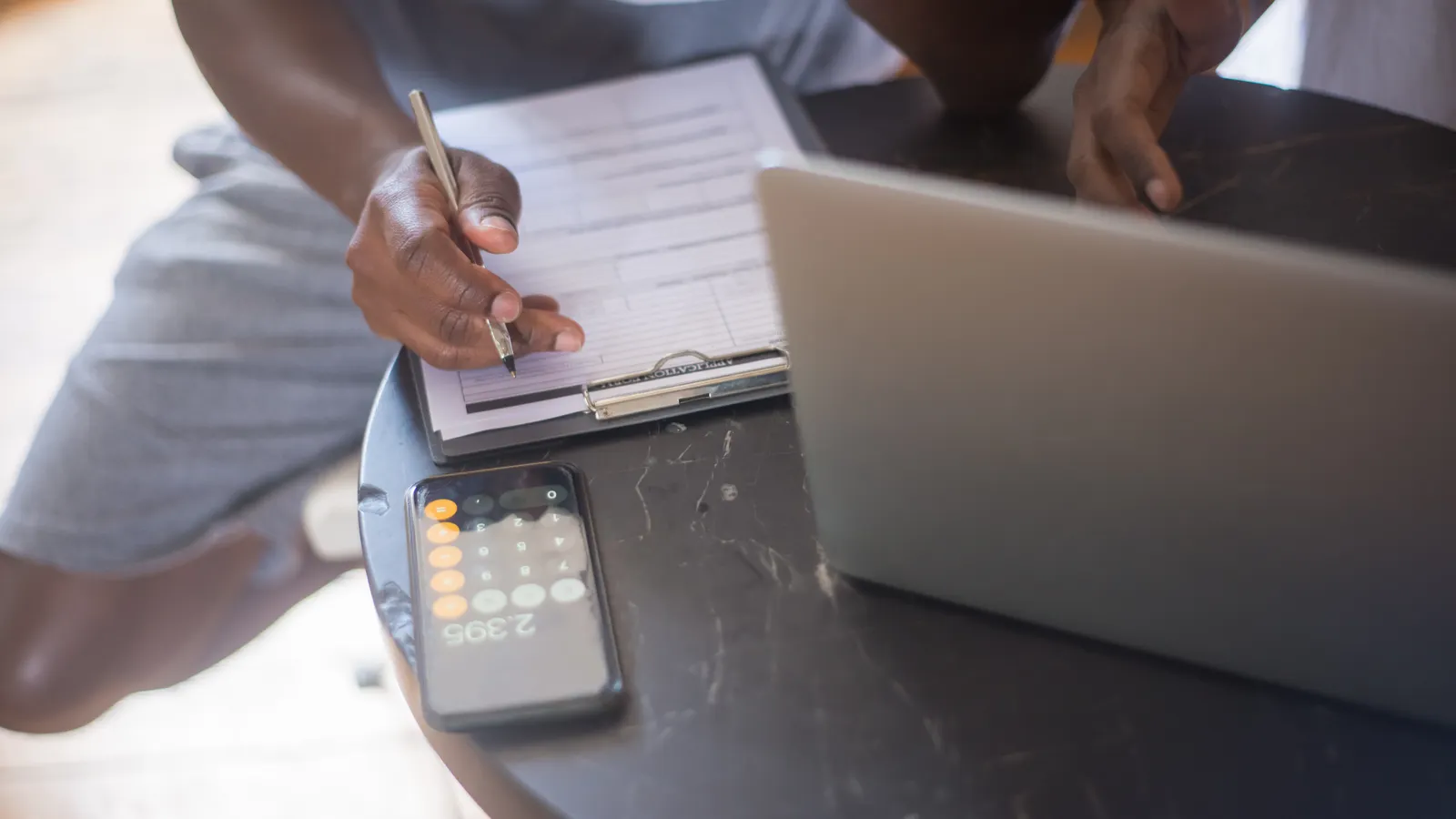 Person reviewing a checklist on paper at a desk with a laptop nearby