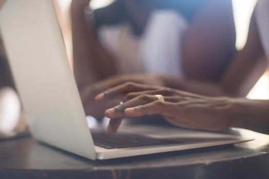 A detailed close-up of hands typing on a laptop keyboard indoors, showing focus and engagement.