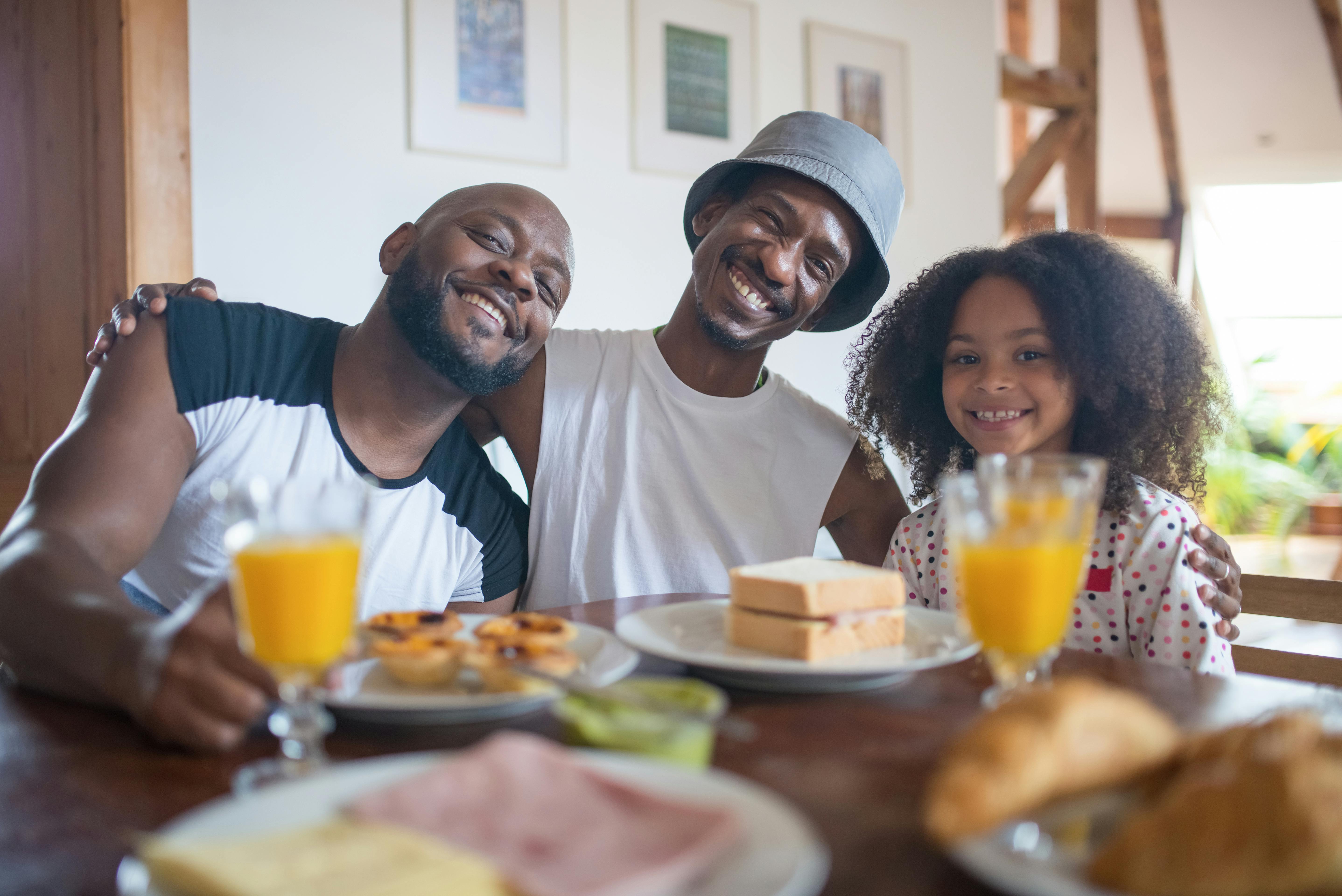 a happy family smiling while sitting near the table with food and drinks