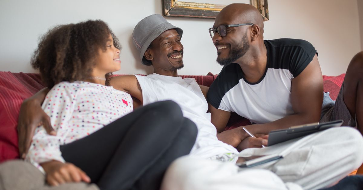Joyful family bonding on a couch, exchanging smiles and conversations in a comfortable home setting.