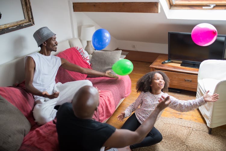 Men And A Young Girl Playing Balloons Together